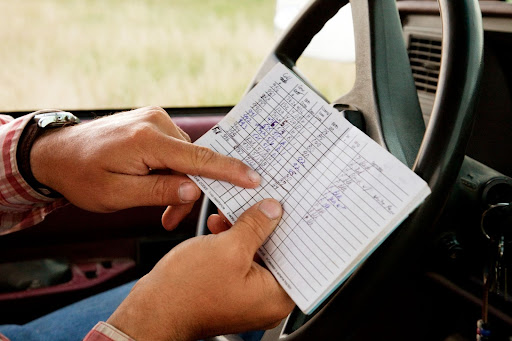 hand holding a list on a steering wheel